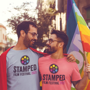 2021 STAMPED Film Fest featured event image for Foo Foo Festival. Features two gay men wearing Stamped Film Festival tshirts with gay pride flag in hand.